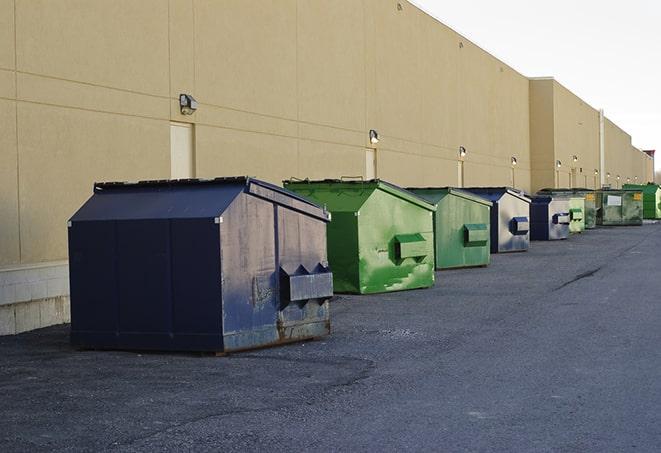 a construction worker unloading debris into a blue dumpster in Gwinn, MI